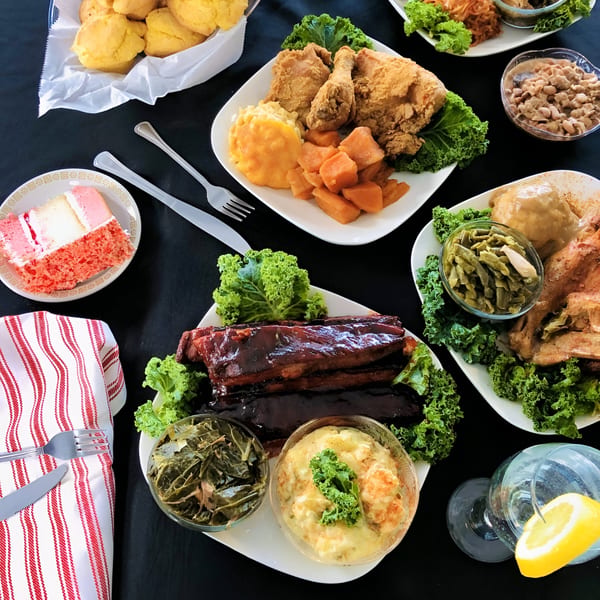 A feast of soul food dishes including fried chicken, ribs, collard greens, and cornbread.